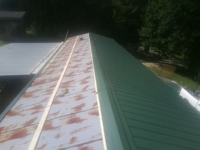 Old rusted panels beside newly installed green metal roofing — Wind Damage Roof Repair by Roofing Brothers in Cedarburg