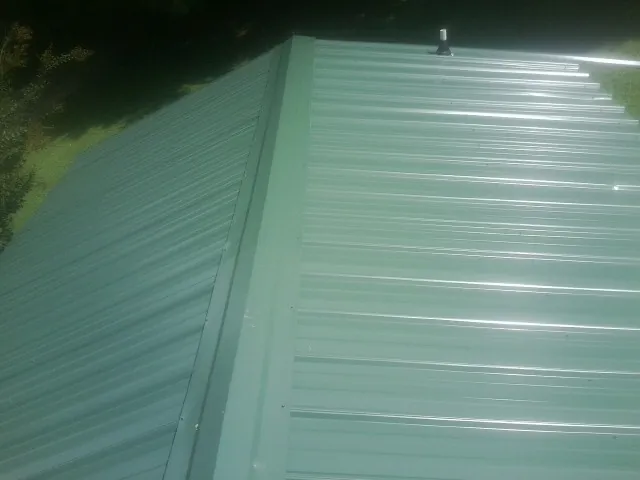 New green metal panels meeting at the ridge of a roof — Flat Roof Repair work by our crew in Cedarburg