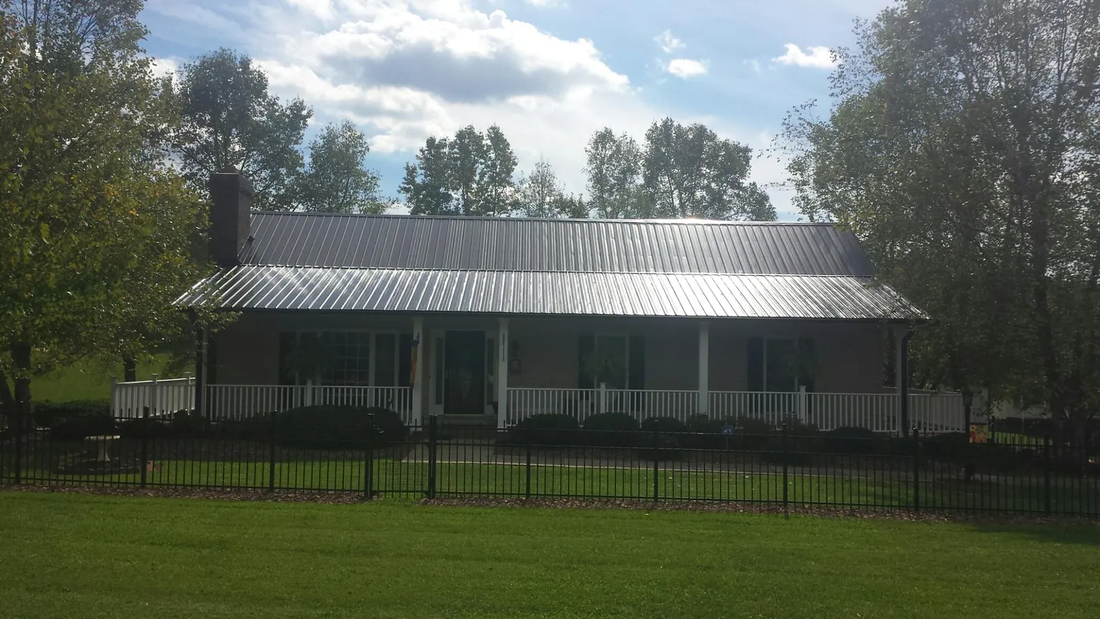 Gray metal roof on a brick ranch with a full width front porch — Gutter Guard Installation work by our crew in Cedarburg