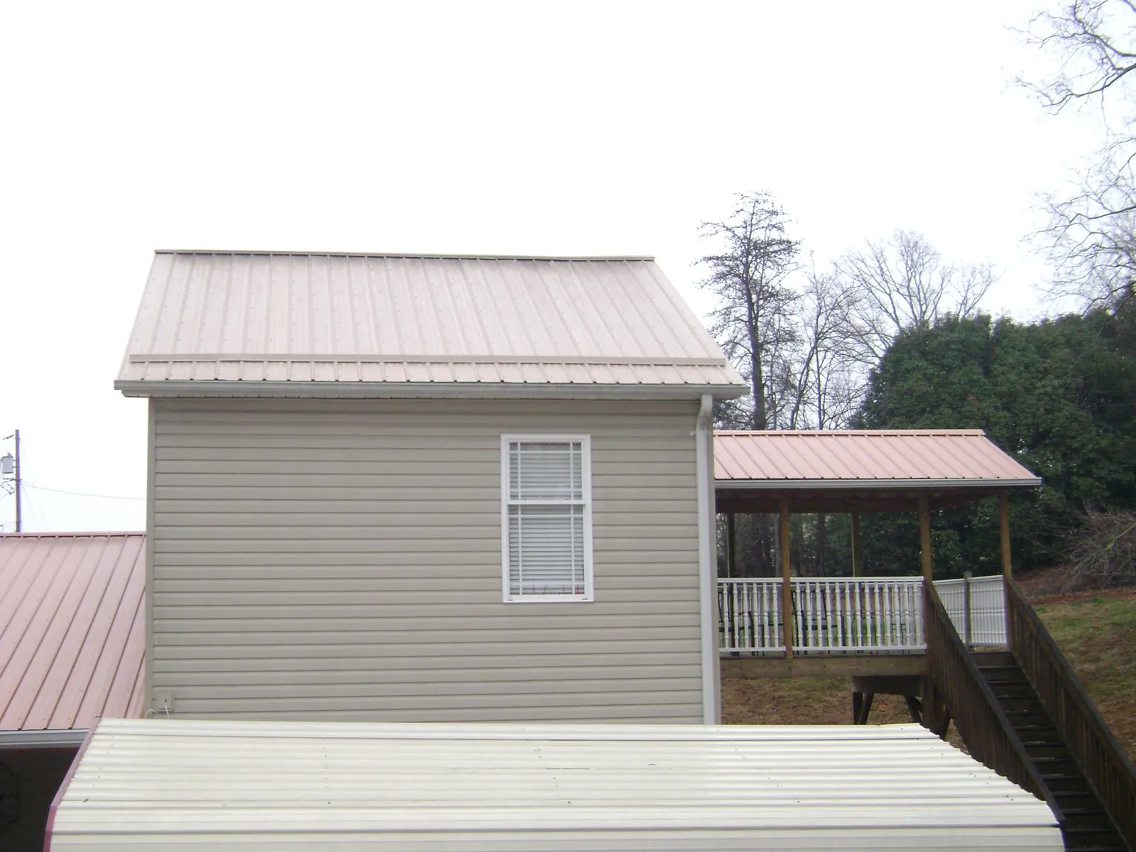 Tan metal roofs on a two story addition and attached porch, from a Roof Replacement job in Cedarburg