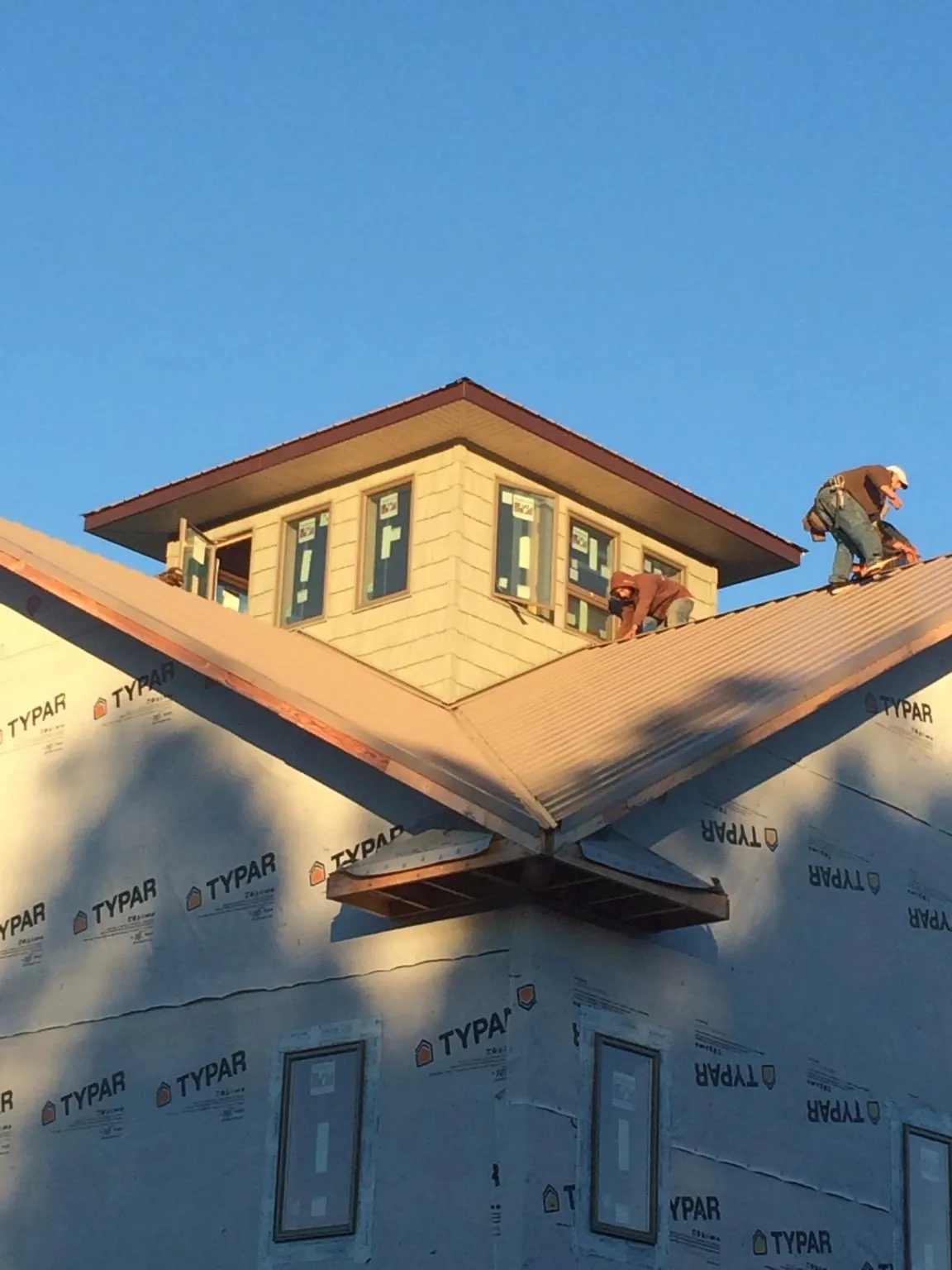 Roofers working around a rooftop cupola on a new metal roof at sunset — Roof Waterproofing in Cedarburg by Roofing Brothers